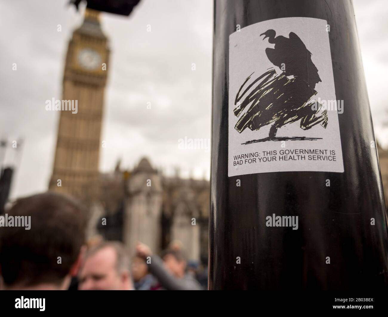 Streetart sättigt die Auswirkungen der britischen konservativen Regierung auf den nationalen Gesundheitsdienst mit Big Ben in der Hintergrundunschärfe. Stockfoto
