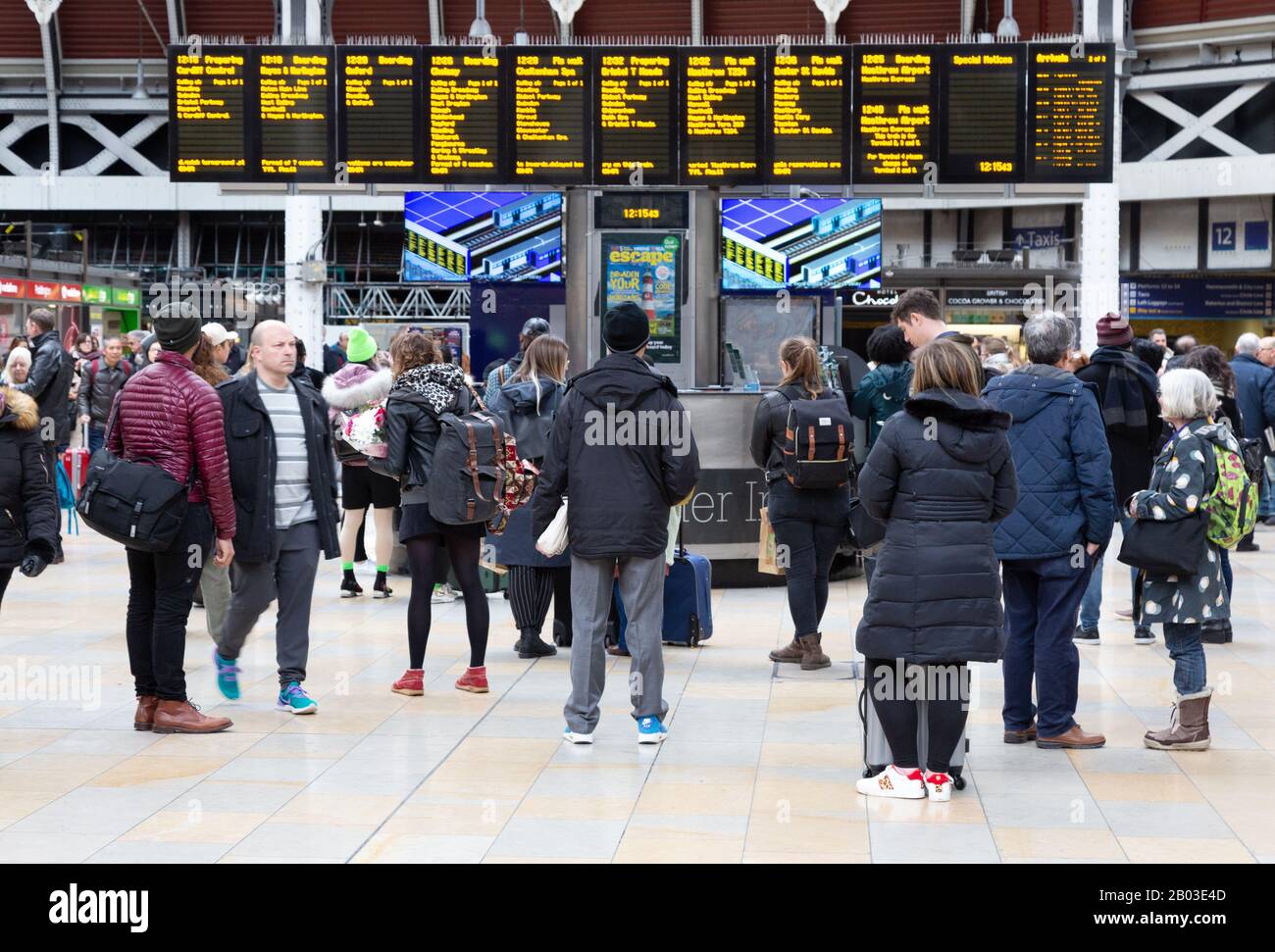 Zugpassagiere mit Blick auf den Abfahrts-Bord, Paddington Train Station, Paddington London UK Stockfoto