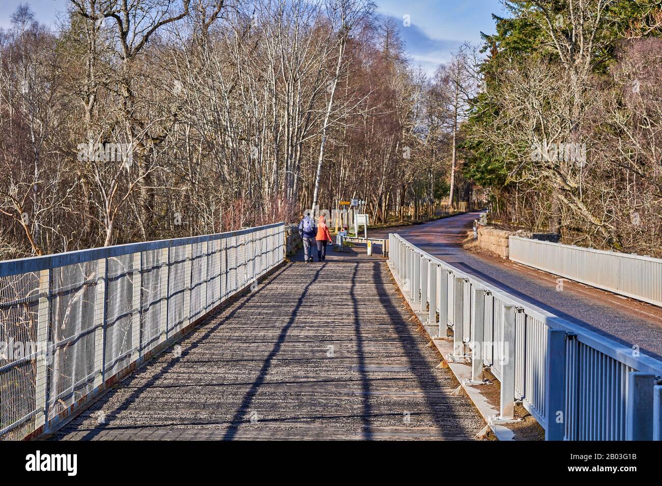 CARRON VILLAGE MORAY SCOTLAND WALKERS AUF DER EINZIGARTIGEN CARRON ROAD UND DER ALTEN EISENBAHNBRÜCKE, DIE DEN FLUSS SPEY ÜBERQUERT Stockfoto