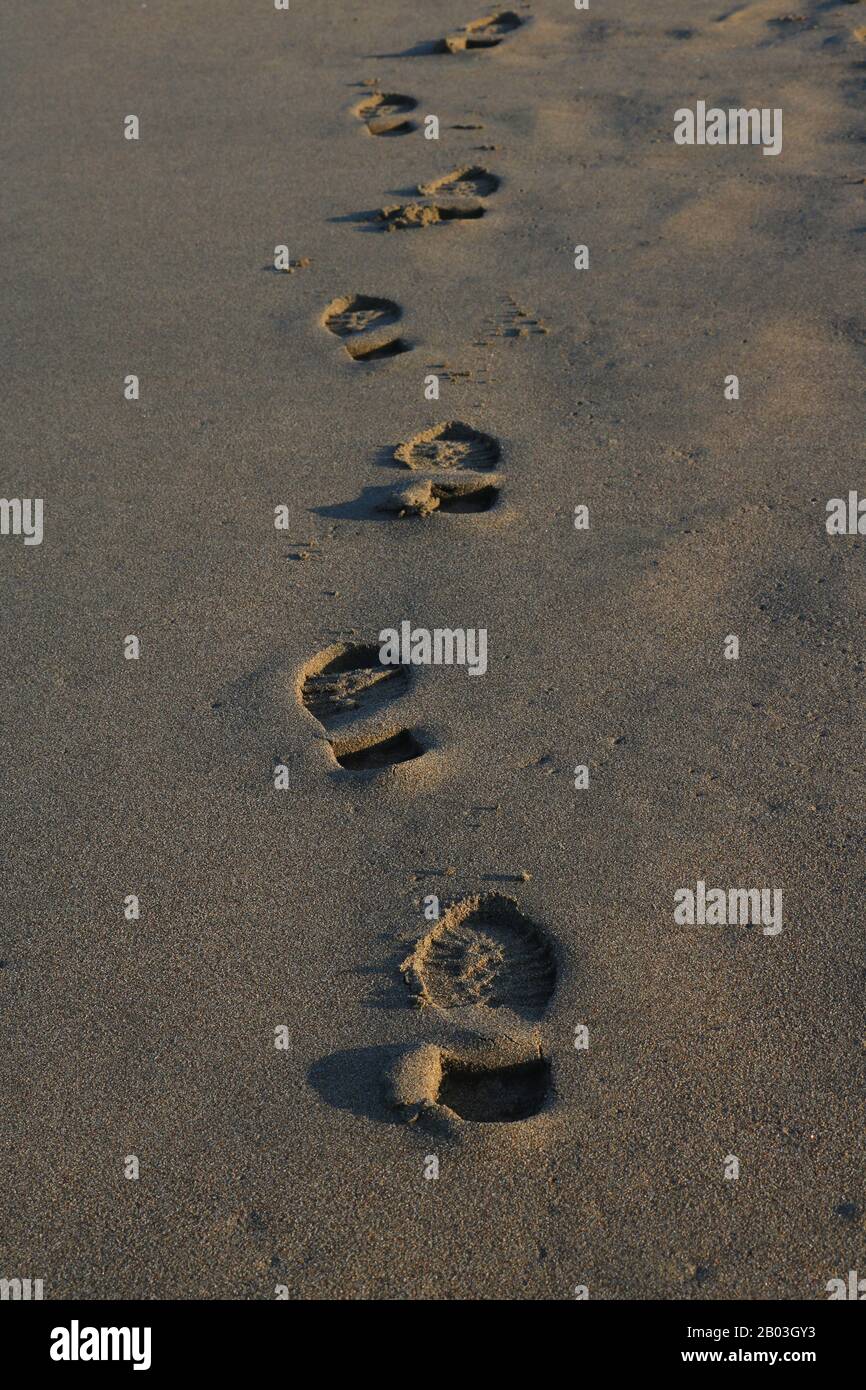Wandern und Entspannen am Strand und menschliche Fußabdrücke auf dem Sand in der Wintersaison. Stockfoto