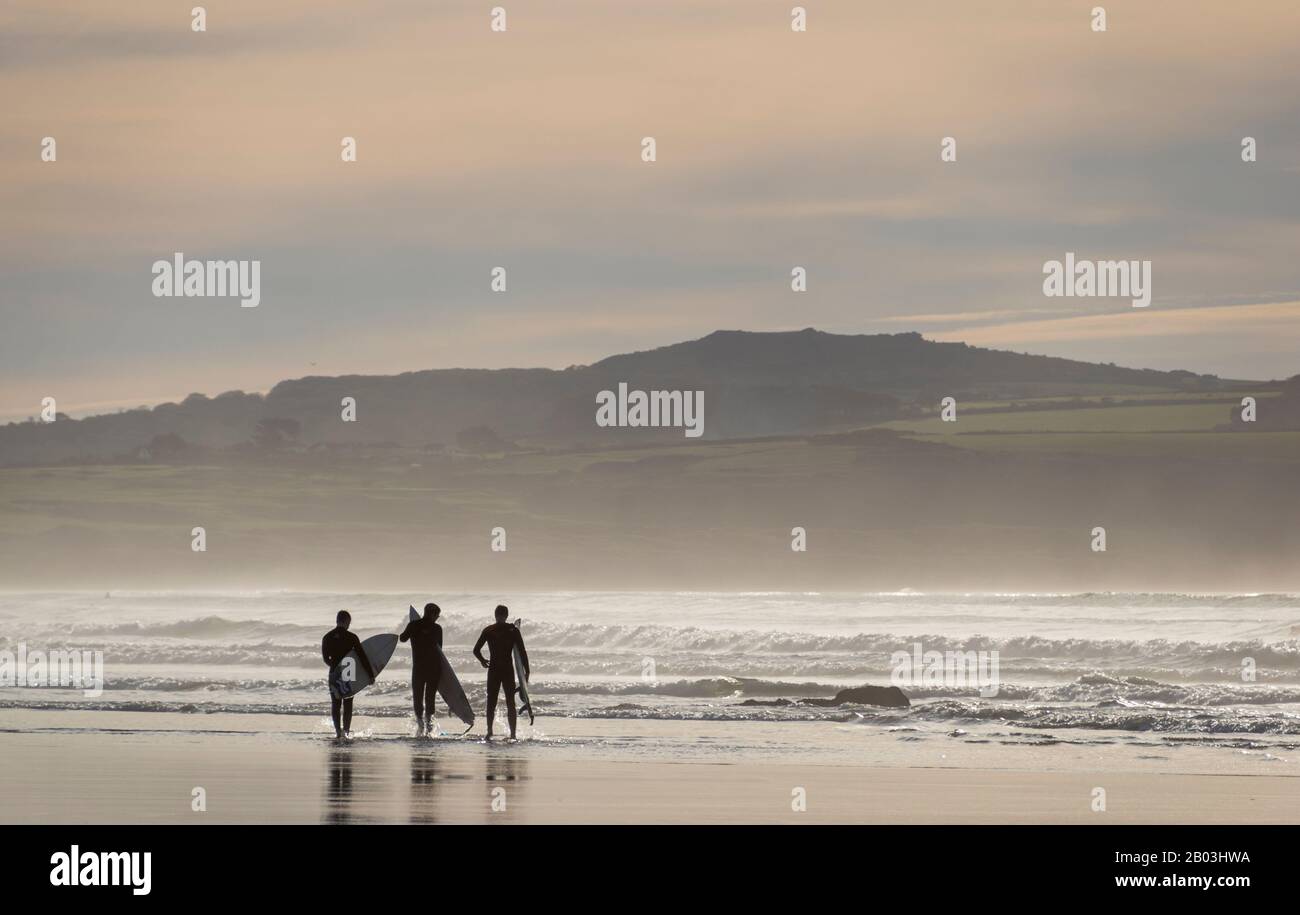Surfer, die ihre Bretter am Strand in Godrevy, Cornwall, Großbritannien tragen Stockfoto