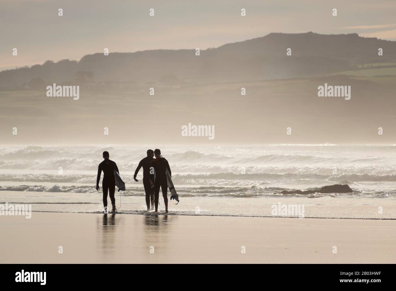 Surfer, die ihre Bretter am Strand in Godrevy, Cornwall, Großbritannien tragen Stockfoto