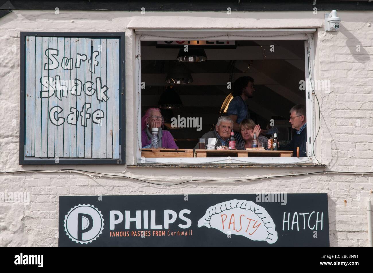 Kunden, die von ihrem Fenster-Tisch im Surf Shack Café aus das Leben beobachten, beobachten, wie sie auf der Wharf Road in St Ives, Cornwall, England, vorbei fahren. Stockfoto
