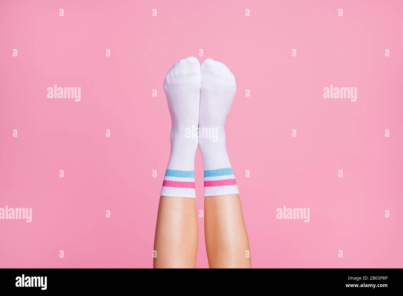 3/4-Nahaufnahme der schönen vertikalen femininen Beine mit weißen weichen Baumwollsocken bequeme Socken neue Brandy-Kollektion isoliert über Pink Stockfoto