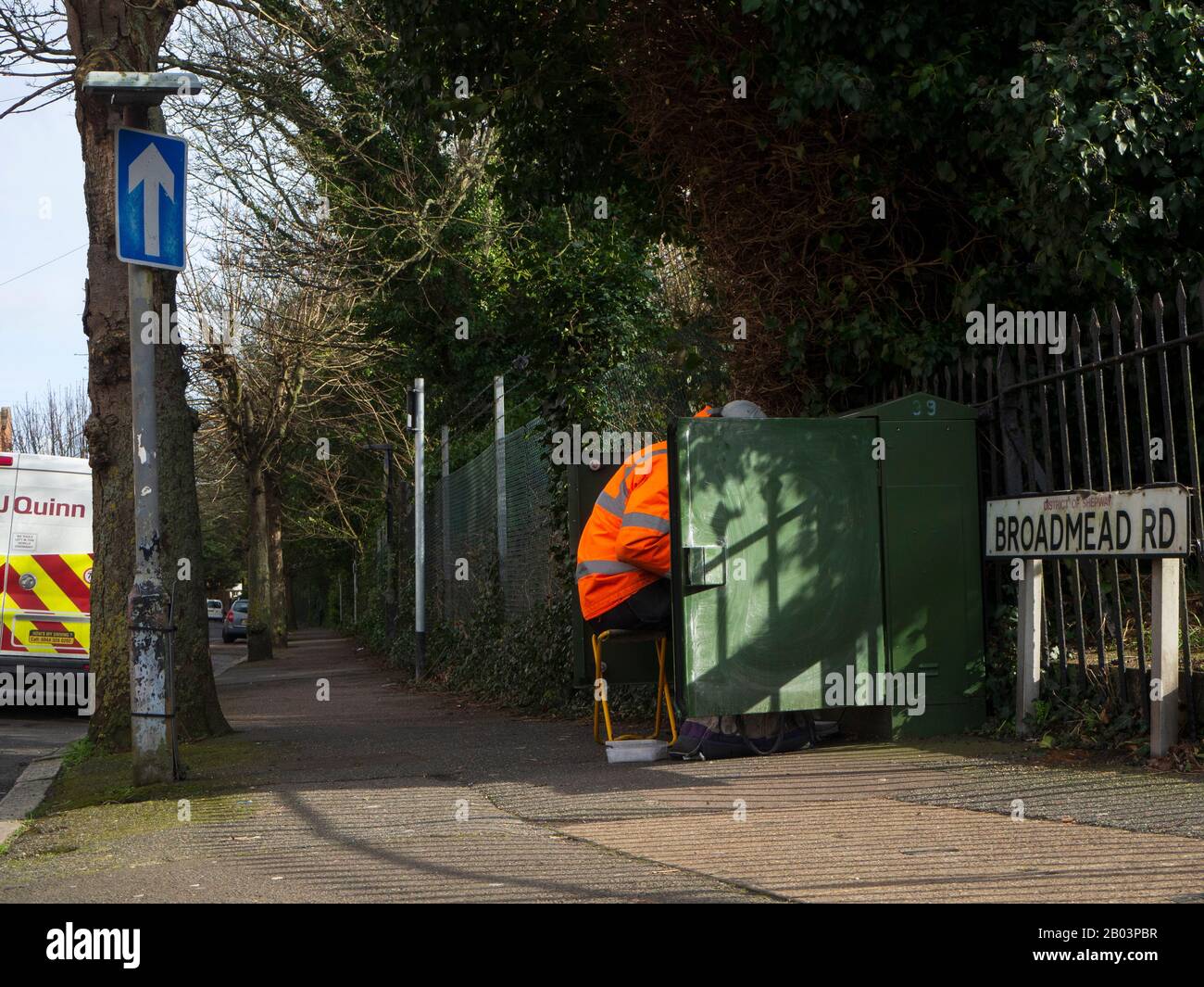 Telekommunikationsingenieur, der an einer grünen Schrankbox in einem Wohngebiet arbeitet Einbahnstraße Stockfoto