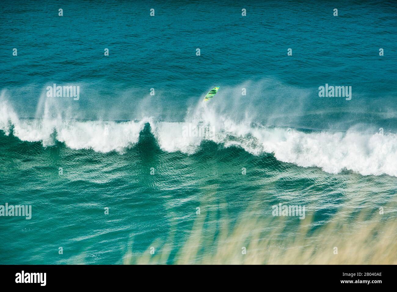 Ein Surfbrett fliegt hoch über einer Welle, als ein Surfer die Kontrolle vor Perran Beach, Perranporth, der Küste von Cornwall, Cornwall England verliert Stockfoto