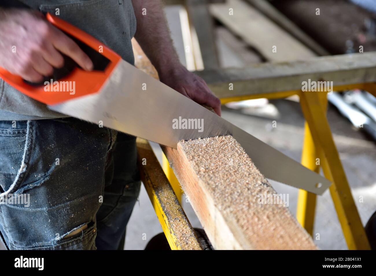 Arbeiter mit Handsäge durch neue Holzbalken schneiden Stockfoto