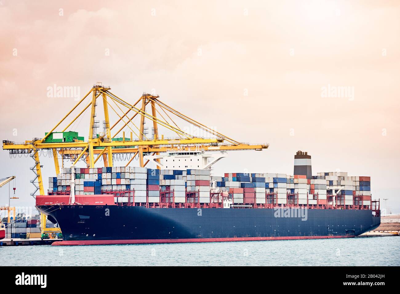 Schiffskräne, die Container auf dem Schiff im Hafengebiet laden. Transportindustrie und Versandlogistik. Exportieren und Importieren von Bussinen Stockfoto