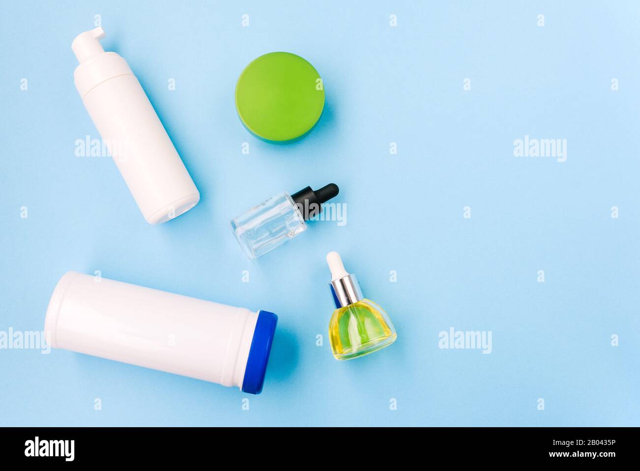 Weiße Kunststoffflaschen auf blauem Hintergrund. Kosmetikprodukte für Frauen, Schaum zum Waschen, Grundierung für Make-up und Öl. Gesundheit und Schönheit Stockfoto