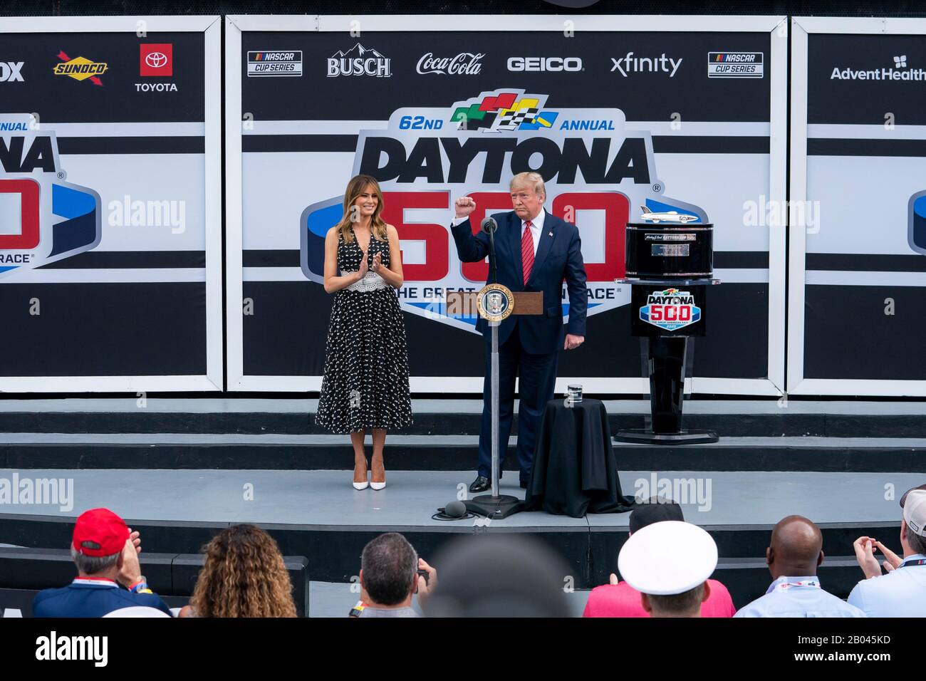 US-Präsident Donald Trump gibt Bemerkungen ab, als First Lady Melania Trump auf dem Daytona International Speedway vom 16. Februar 2020 in Daytona Beach, Florida, zu sehen ist. Trump diente als offizieller Starter des NASCAR Daytona 500 Autorennen und fuhr in der Präsidentenlimousine rund um die Strecke. Stockfoto