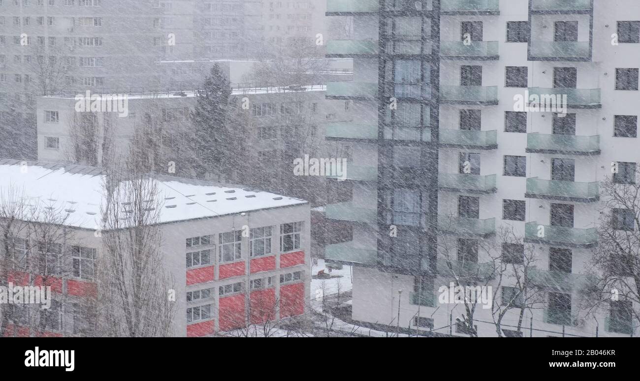 schneeblozzard bläst Schneeflocken seitlich, mit einem modernen, hohen Apartmentgebäude im Rücken, in Bukarest, Rumänien. Stockfoto