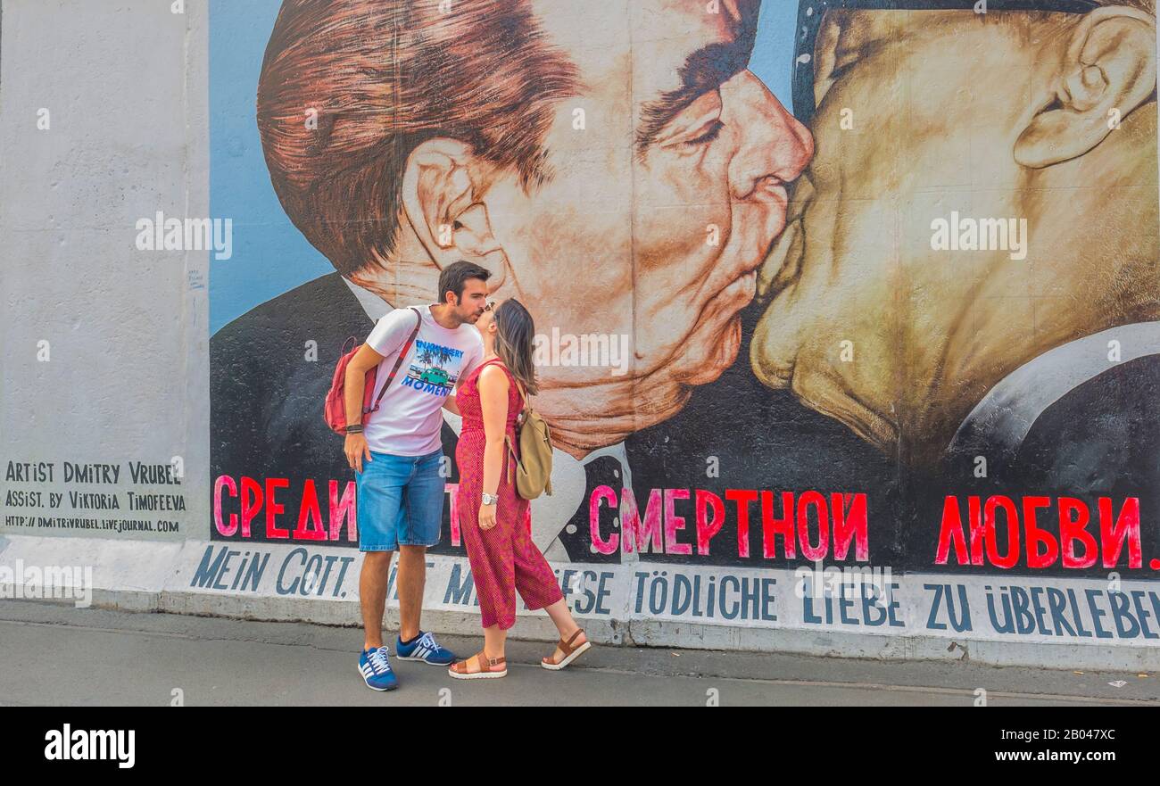 Junges Paar küsst sich vor der Wandbemalung an der Ostseitengalerie Stockfoto