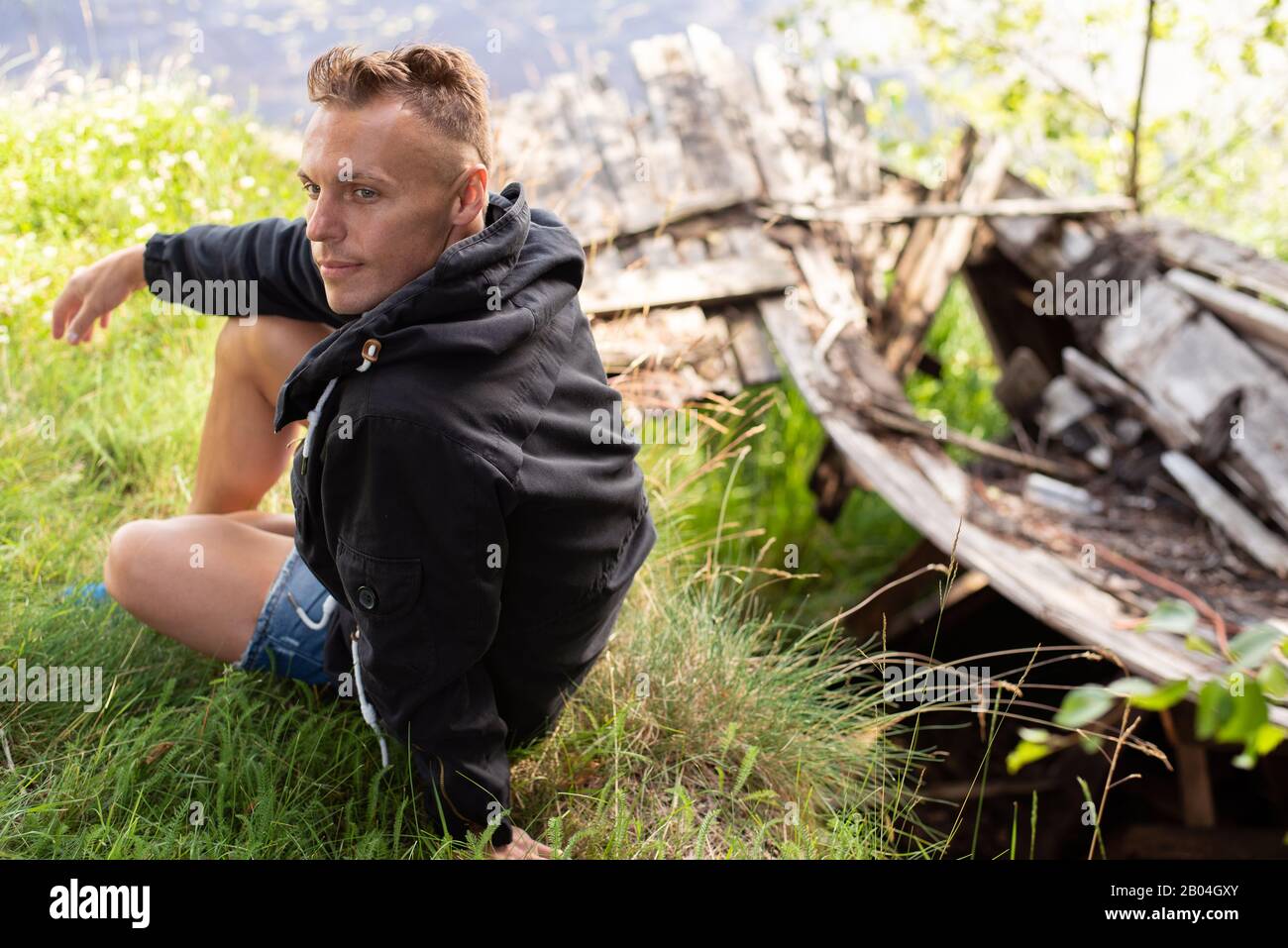 Ein Mann am Ufer des Sees, neben einem umfallenden Boot. Stockfoto