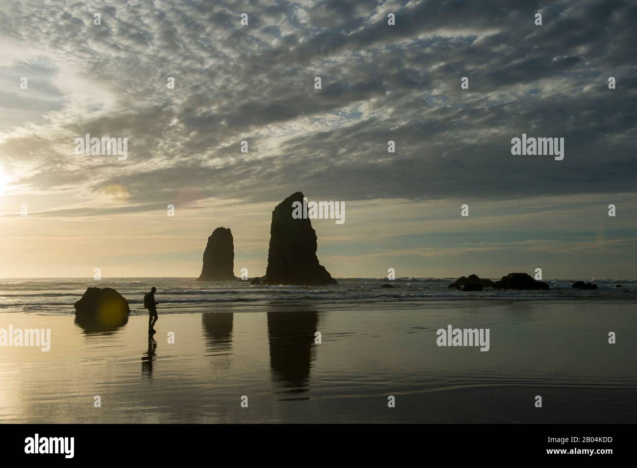 Menschen, die am Cannon Beach an der nördlichen Oregon Coast, USA, spazieren gehen, mit im Hintergrund befindlichen Seestapeln. Stockfoto