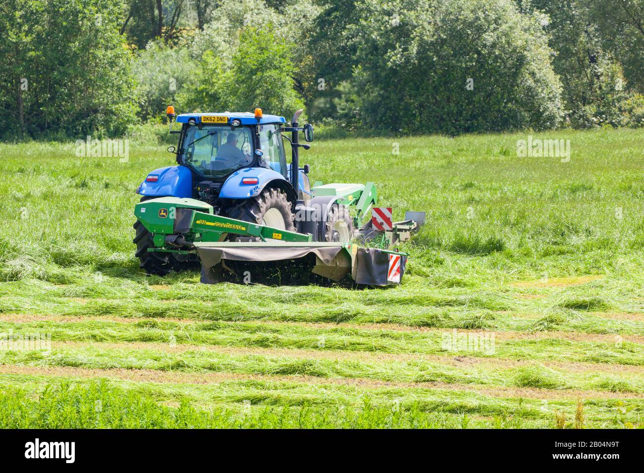 Farmer, der Traktor fährt, der Gras für Silage in Cheshire Farmland England UK schneidet Stockfoto