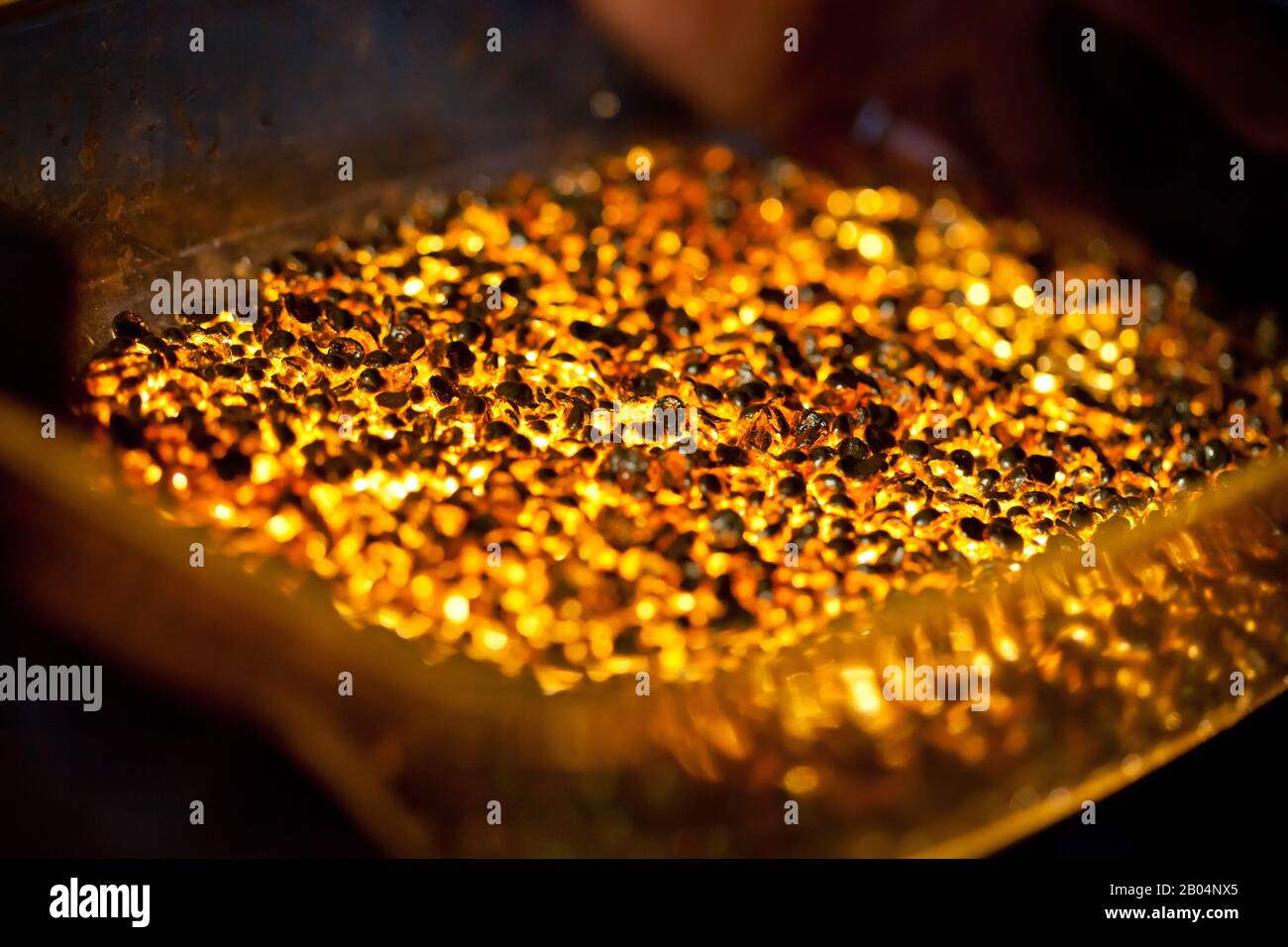 Nahaufnahme von vielen Ingots schmelzendem Gold, heiß glänzenden Metallteilen, die leuchten, niemand Stockfoto