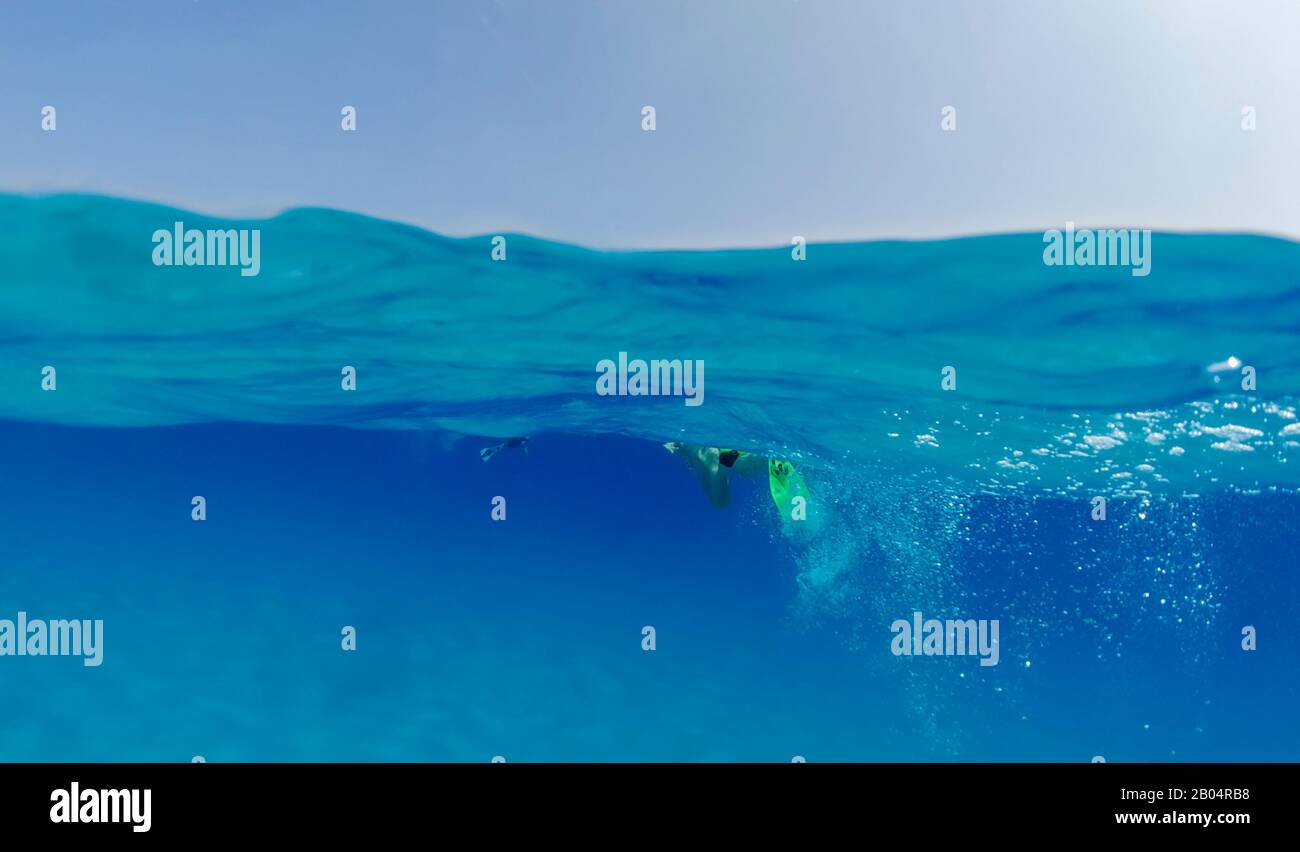 Ein Tourist in Flippern schwimmt im Meer und blickt auf den sandigen Grund unter Wasser. Geteilte Unterwasserfotos Stockfoto