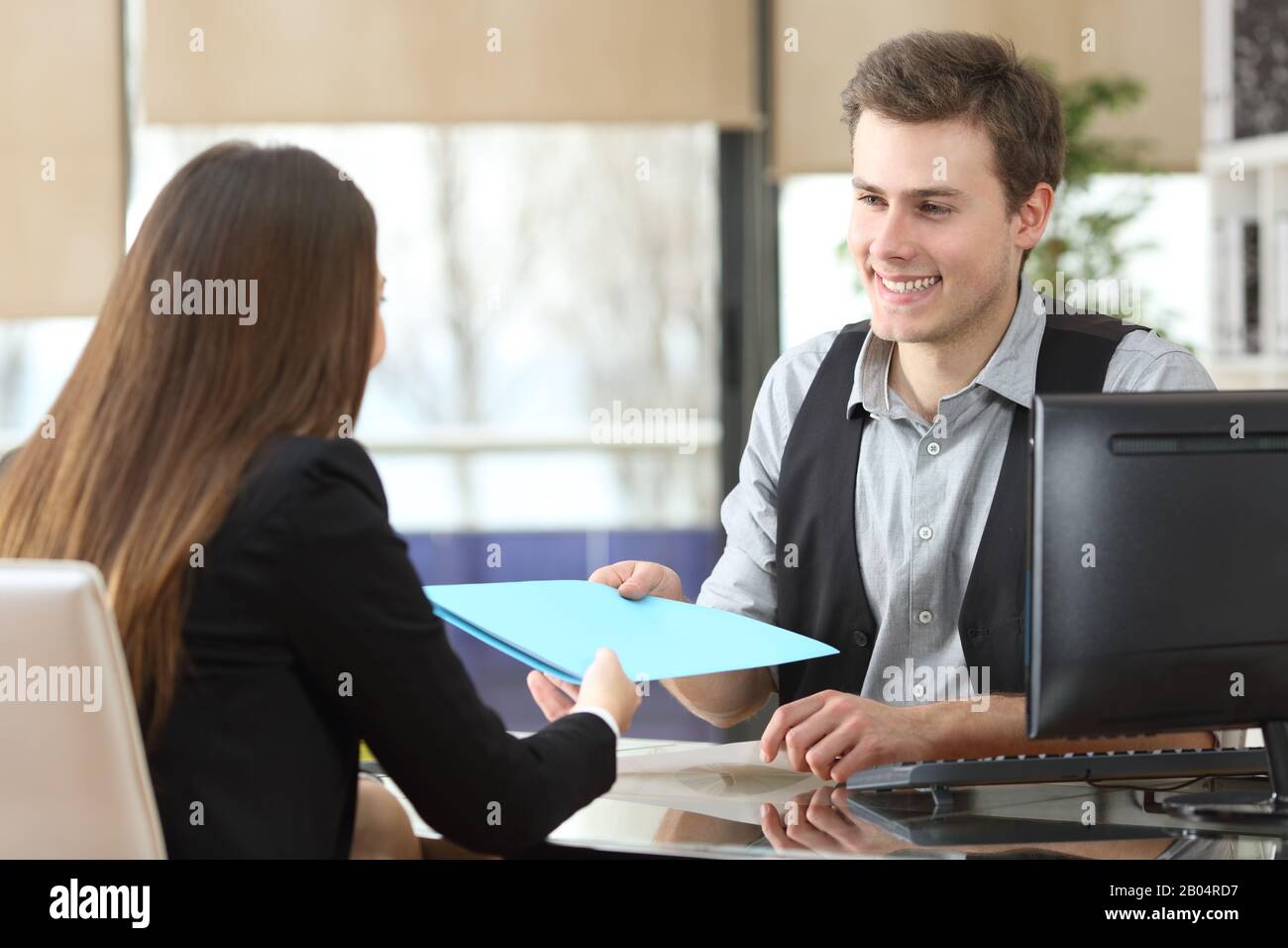 Ein Geschäftsmann, der einem Kunden, der während eines Interviews im Büro sitzt, Dokumente gibt Stockfoto