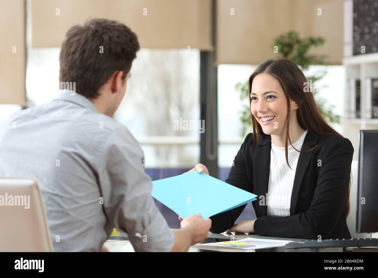 Mitarbeiter, der seinem glücklichen Vorgesetzten beim Gespräch im Büro Ordner gibt Stockfoto