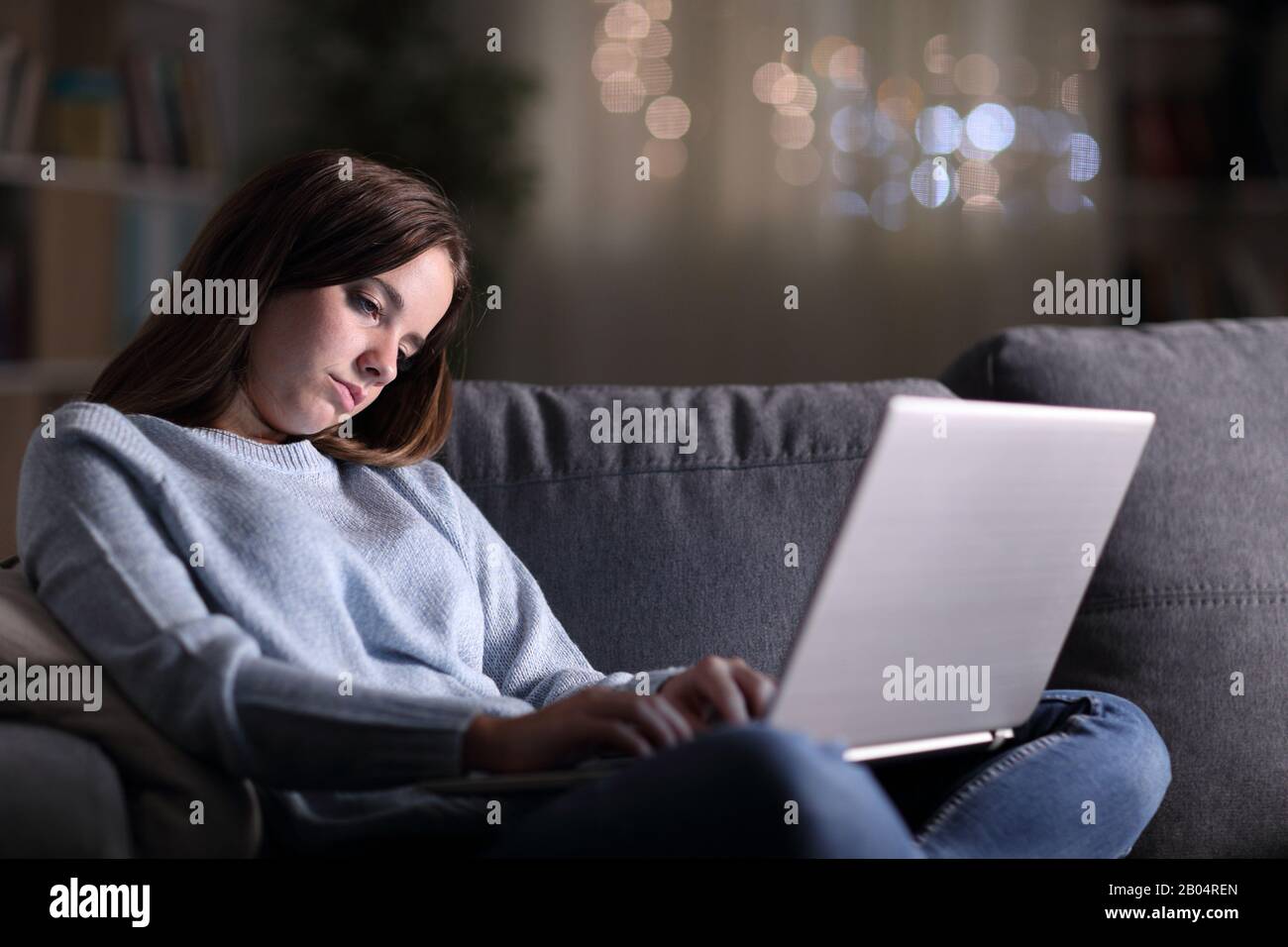 Müde schlafende Frau mit Laptop spät in der Nacht auf einer Couch zu Hause sitzen Stockfoto