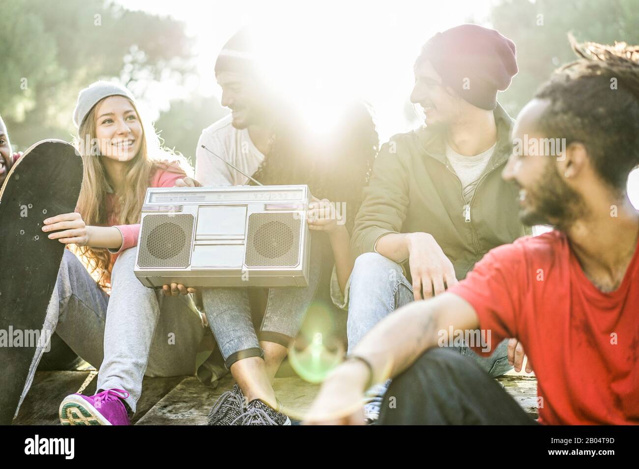 Fröhliche Skater und Breakdancer Freunde hören Musik und lachen im Stadtpark - Junge Leute haben Spaß mit tragbarem Boombox-Stereo - Jugend konce Stockfoto