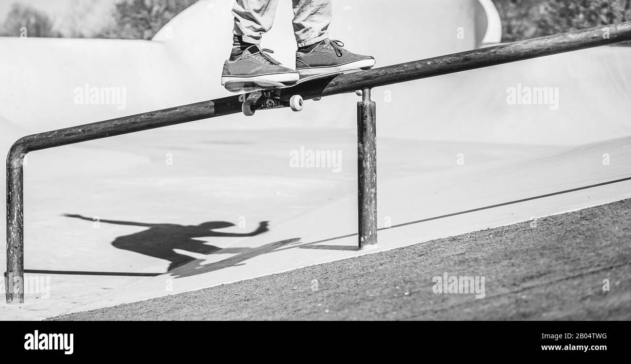 Skater, der Tricks auf der Rampe ausführt - Junger Mann, der im Skateboard-Park Spaß am Extremsport hat - Fokus auf Füße - Schwarz-Weiß-Bearbeitung Stockfoto