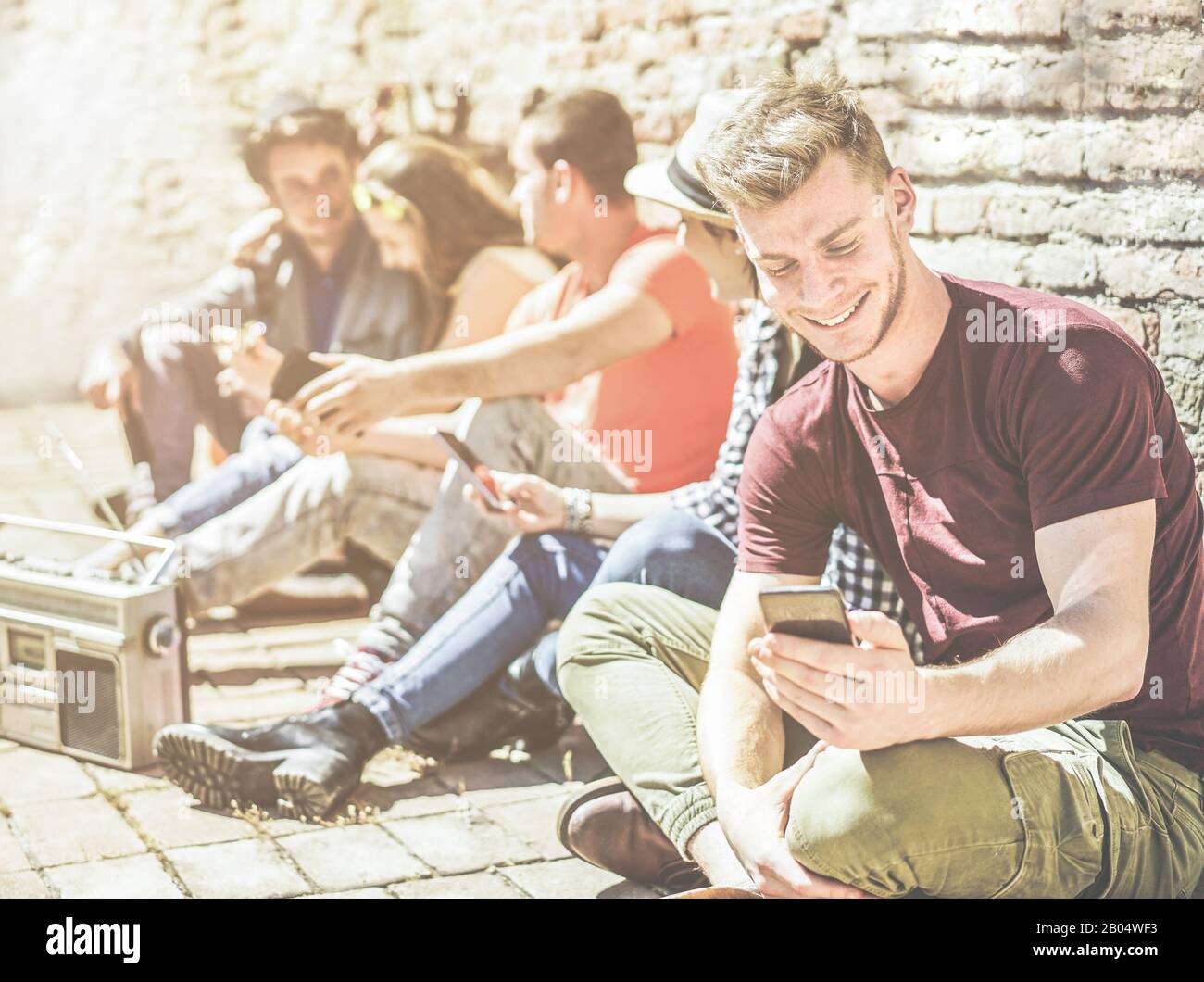 Eine Gruppe von Teenager-Freunden, die mit Mobiltelefonen im Freien in der Altstadt unterwegs sind - Junge Leute im sozialen Moment, die Musik hören und lachen - Focu Stockfoto