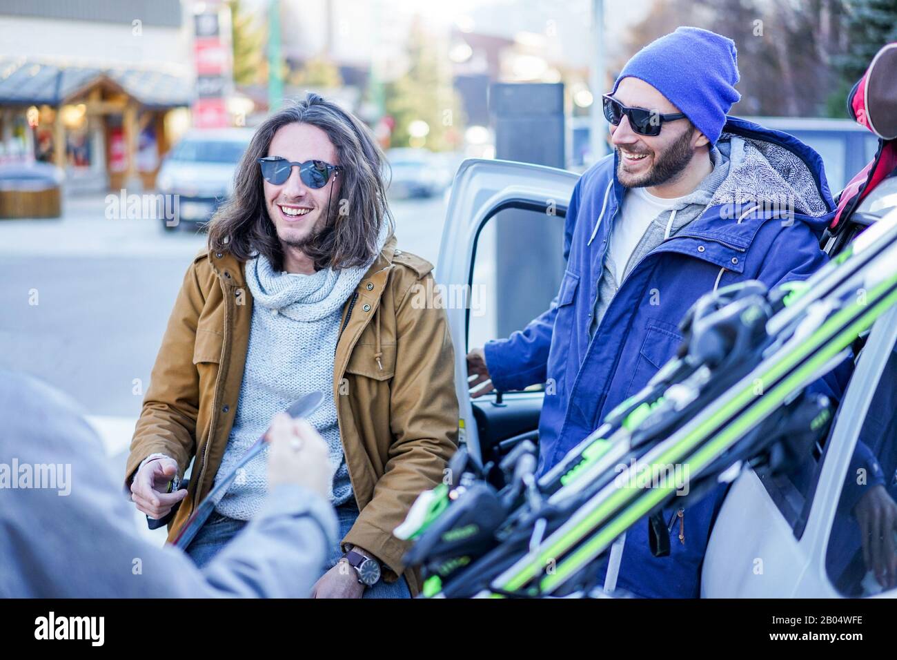 Junge Freunde kamen im Winterurlaubsdorf mit Himmel und Snowboards an - Glückliche Skifahrer, die Spaß haben, das Auto zu entladen - Extremsport, Urlaub und f Stockfoto