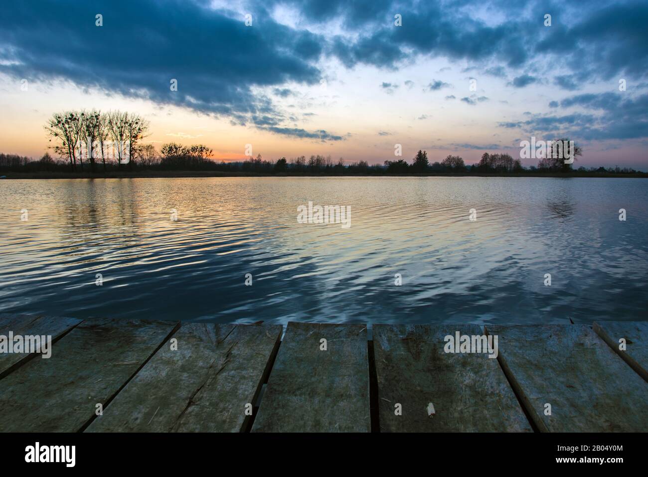 Wolken über dem See nach Sonnenuntergang und eine Holzbrücke, Blick auf den Abend Stockfoto