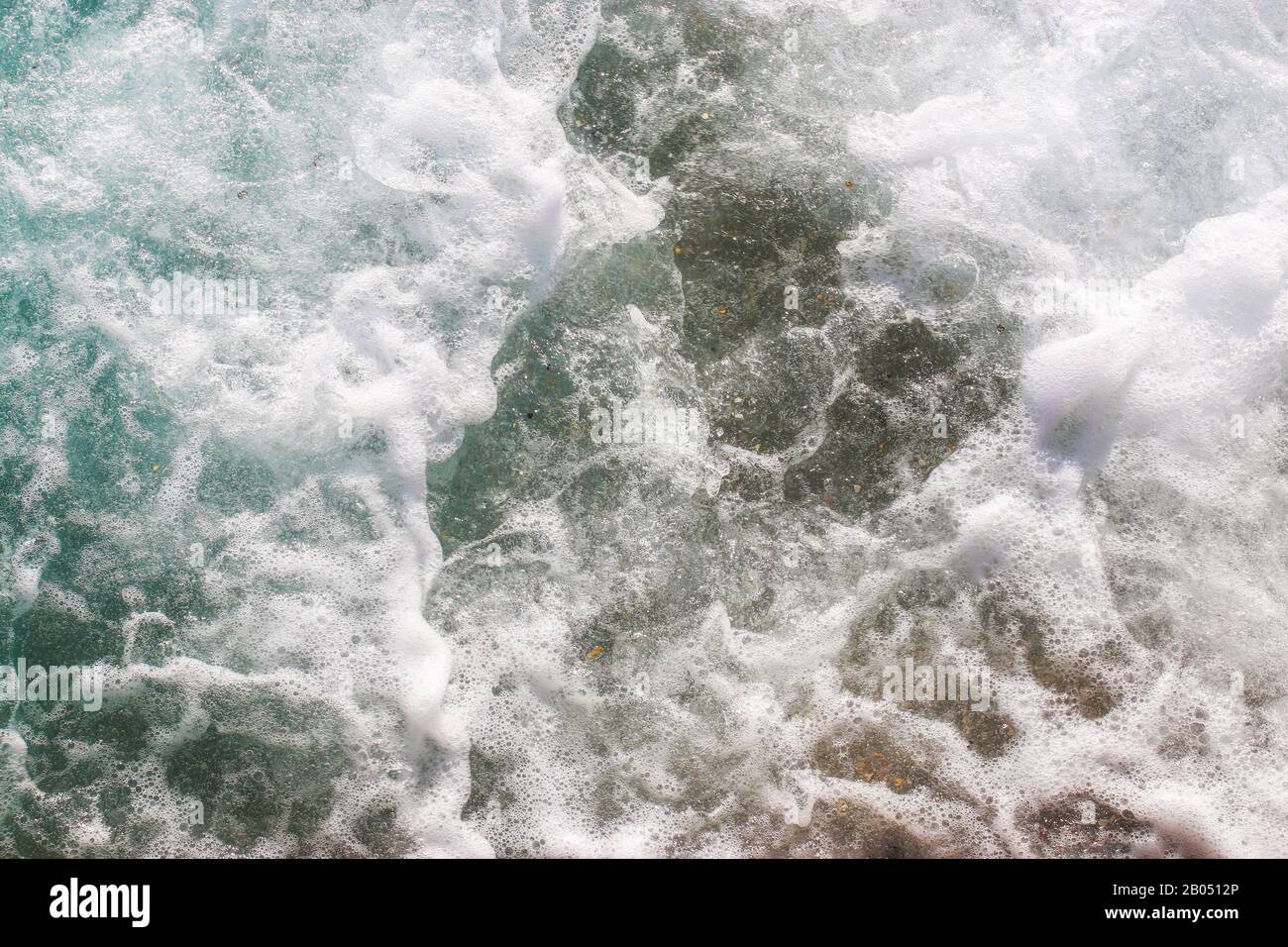 Top View Texturwellen, schäumen und spritzen im Ozean, sonniger Tag. Wunderschönes tropisches Meer im Sommerzeitbild mit Luftbild. Abstrakter Meeresbak Stockfoto