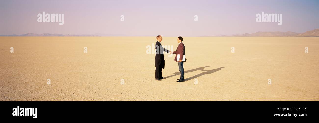 Zwei Geschäftsleute schütteln die Hände in einer Wüste, Black Rock Desert, Nevada, USA Stockfoto