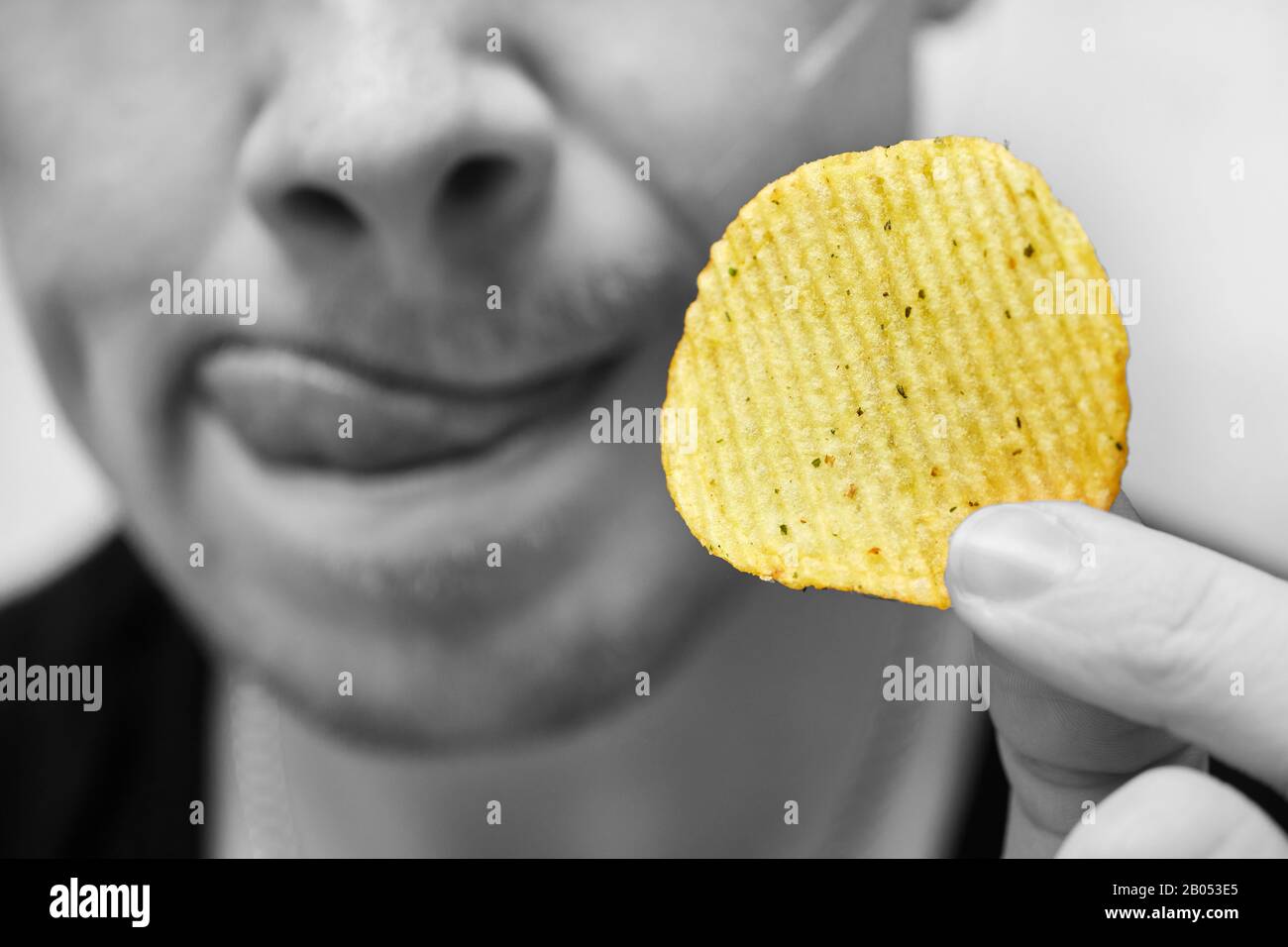 Ein Mann sitzt darin, Chips in der Hand zu halten und sieht sich mit Appetit auf sie an. Nahaufnahme. Stockfoto