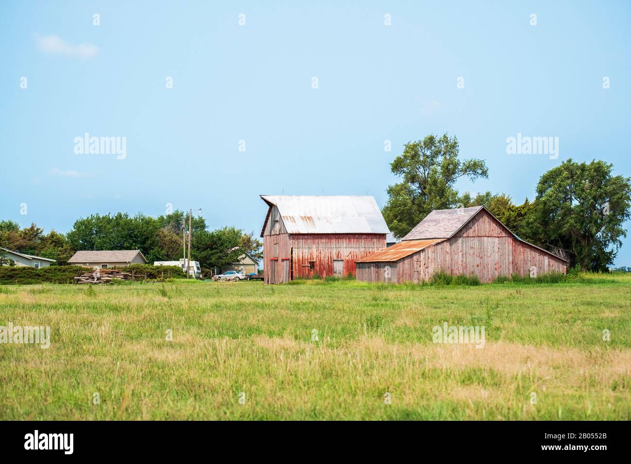 Farm in Kansas mit Grasweide und Holzbarnen und Nebengebäuden mit rostigen Blechdächern. Kansas, USA. Stockfoto