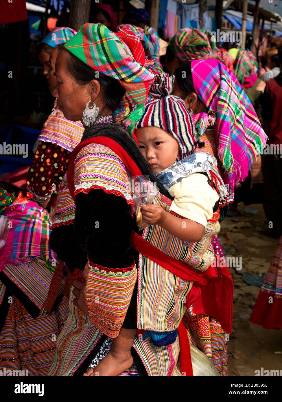Blume Hmong Frau mit Baby auf dem Rücken, Bac ha Sonntag Markt, Lao Cai Provinz, Vietnam Stockfoto