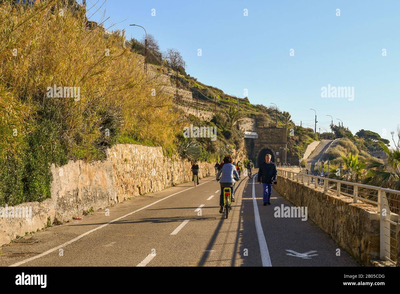 Menschen und Touristen, die an einem sonnigen Tag auf dem Radweg der Blumenriviera spazieren und radeln, Sanremo, Provinz Imperia, Ligurien, Italien Stockfoto