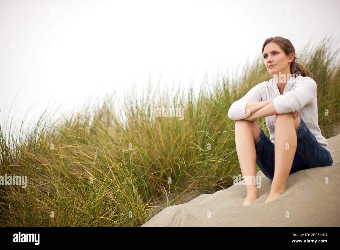 Nachdenkliche Frau sitzt auf einem Strand. Stockfoto