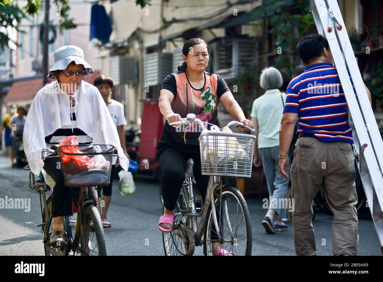 Chinesische Frauen fahren mit dem Fahrrad in der Penglai Road, Huangpu, Shanghai Stockfoto