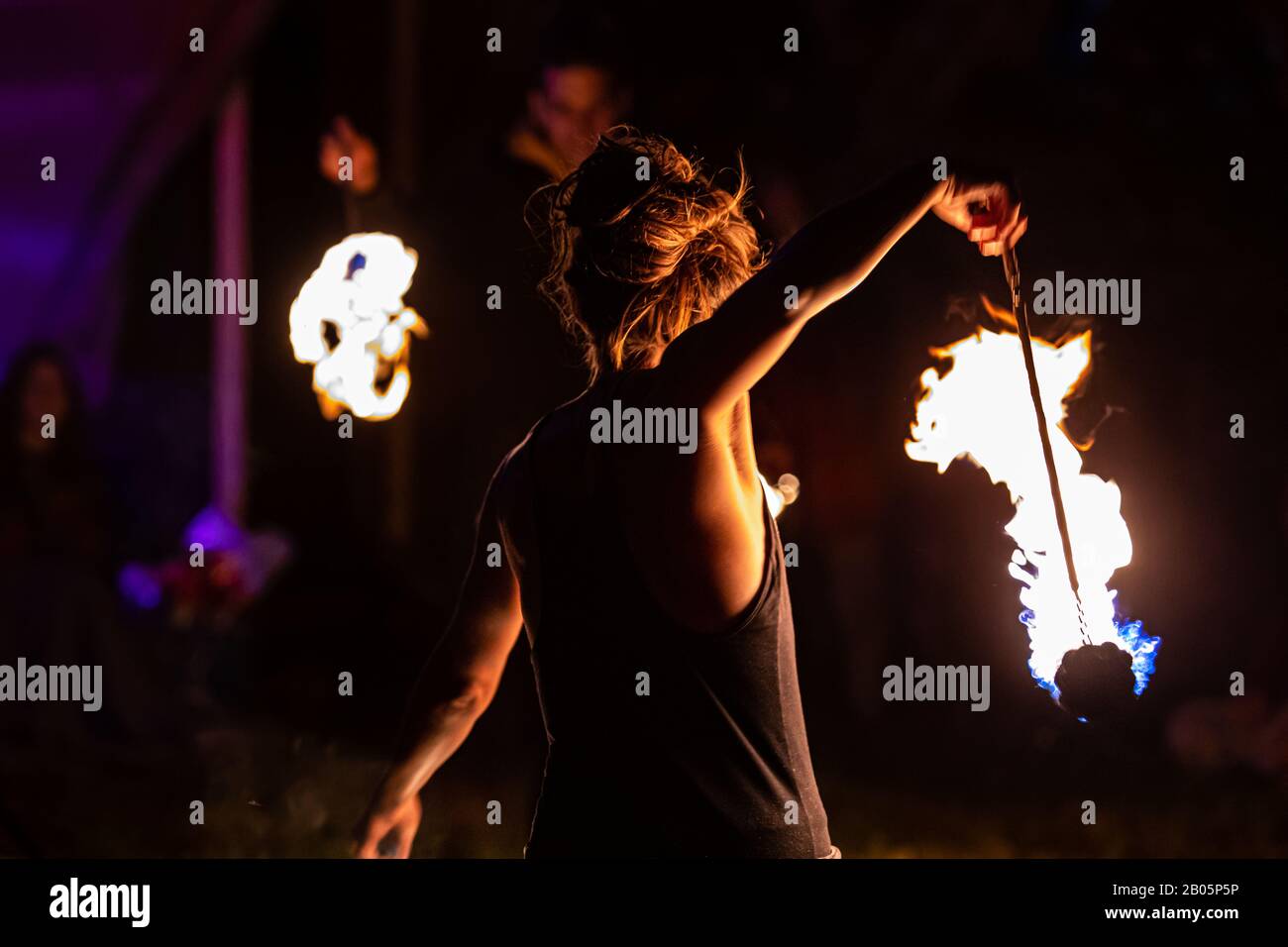 Ein Feuerdarsteller mit traditionellem Poi-Tethered Gewicht wird von hinten gesehen, während eines spirituellen Tanzes auf einem fest, das Erde und Frieden feiert Stockfoto
