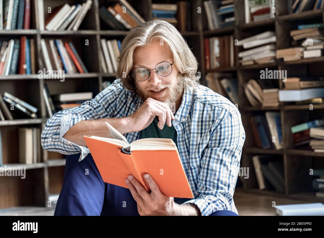Interessierte junge Studentengläser genießen interessante Bücherbibliothek Stockfoto