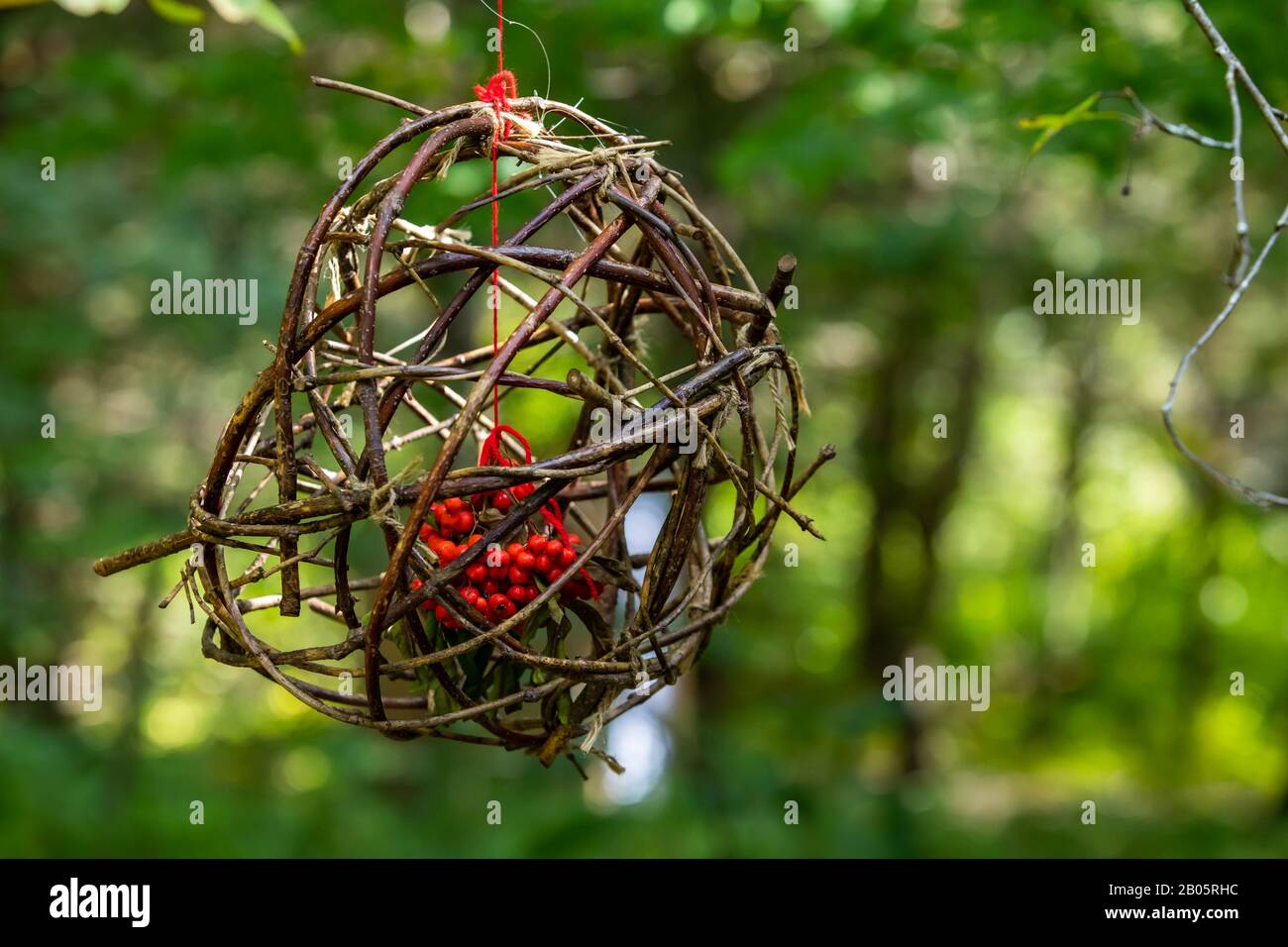 Eine Nahselektive Fokusansicht eines handgefertigten Vogelzubringers, Stöcke und Zweige aus dem Wald, um einen Käfig mit kanadischen Winterbeeren zu schaffen Stockfoto