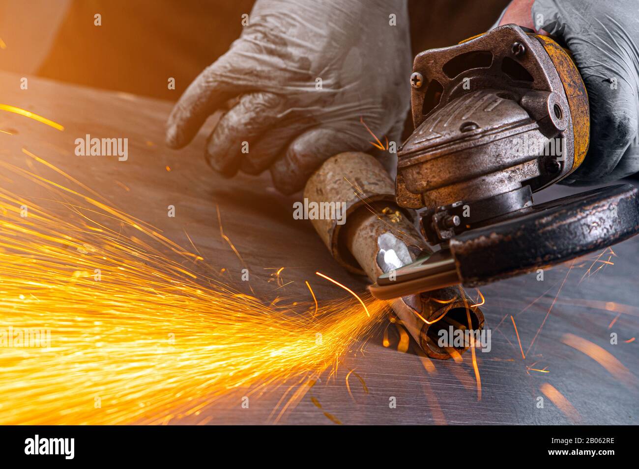 Nahaufnahme eines Mannes sägen Lagermetall Bremsscheibe mit einer Handkreissäge, helle Blitze fliegen in verschiedenen Richtungen, im Hintergrund Tools f Stockfoto