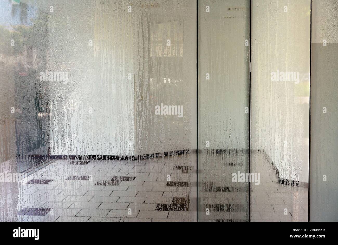 Luftfeuchtigkeit bei heißem Wetter, die das Glas eines leerstehenden Ladens in der Innenstadt durchstreiben Stockfoto