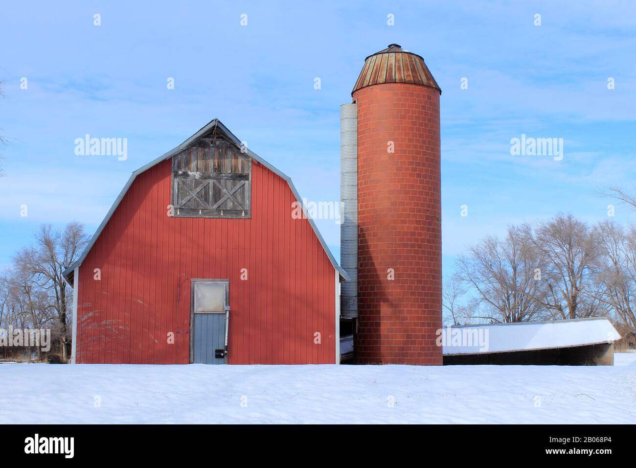 Kansas Red Country Barn mit einem Silo in der Winterzeit mit Schnee im Land. Stockfoto