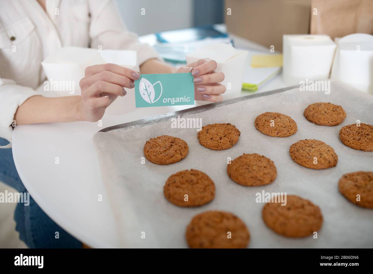 Weibliche Hände, die eine Karte in der Nähe eines Tabletts mit hausgemachten Kuchen halten. Stockfoto