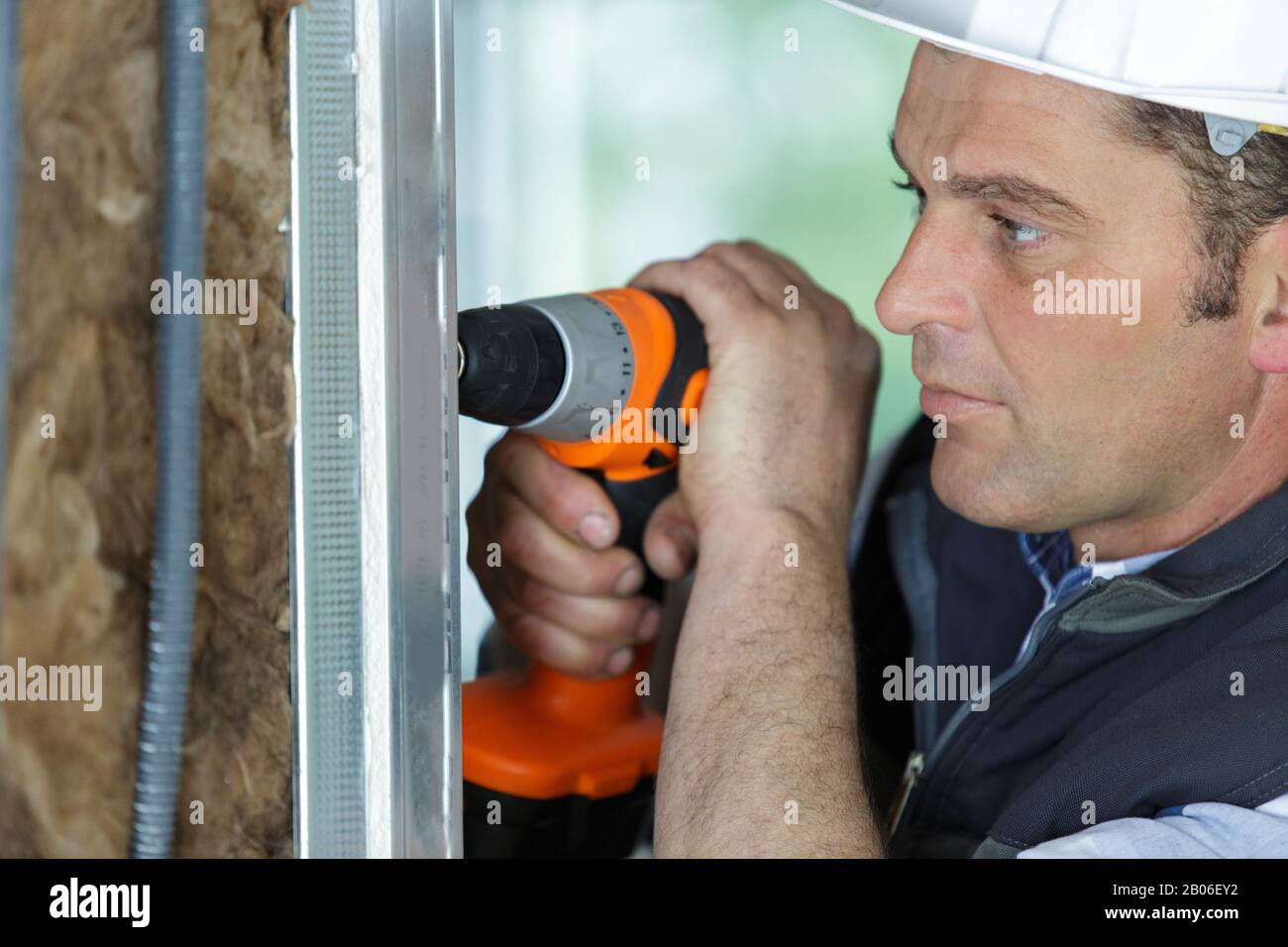 Arbeiter verwendete Bohrmaschine, um Bohrung in der strukturgedämmten Platte zu machen Stockfoto
