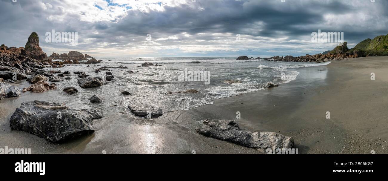 Felsen am Strand, Regenwolken, Westküste, Südinsel, Neuseeland Stockfoto
