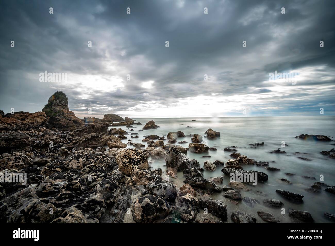 Felsige Küste, Felsen am Strand, dunkle Regenwolken, lange Zeit, Westküste, Südinsel, Neuseeland Stockfoto