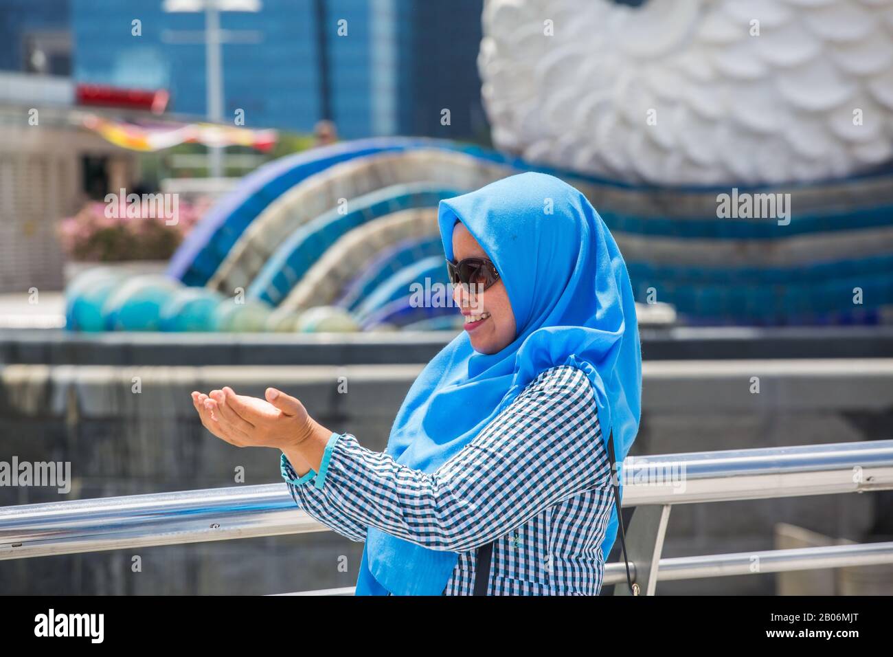 Eine indonesische Dame, die einen blauen Schleier trägt, der für die Aufnahme posiert, Singapur. Stockfoto