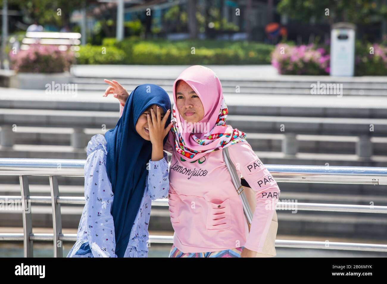 Indonesische malaiische Teenager im Hijab-Schleier posieren für ein Gruppenfoto, eine ist ausdruckslos schüchtern und eine andere Dame ist aufgeschlossen. Merlion Park. Singapur. Stockfoto