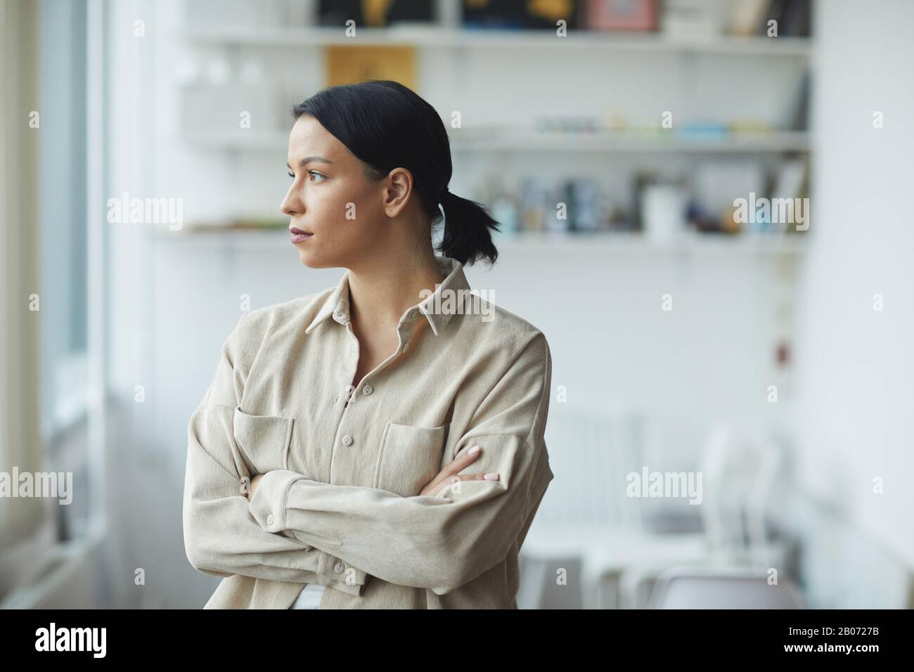 Porträt einer nachdenklichen jungen Geschäftsfrau in legerer Kleidung, die im Büro steht und wegschaut Stockfoto